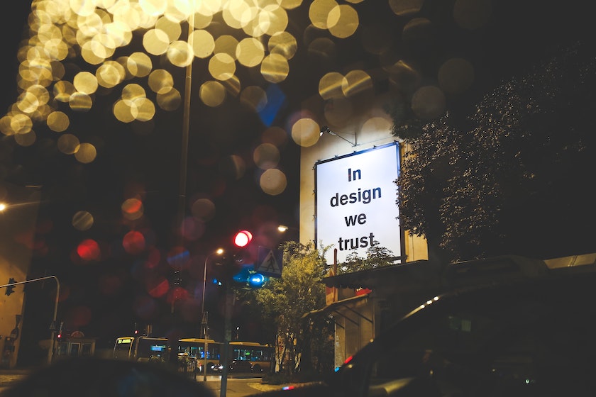 Foto einer Werbetafel mit der Aufschrift "In design we trust".
