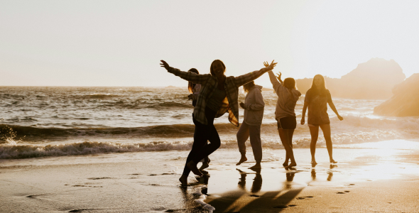 A group of Gen Zalpha playing on a beach at sunset