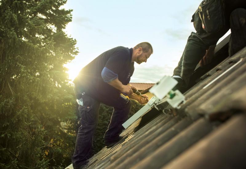 Mann montiert Photovoltaik auf einem Dach