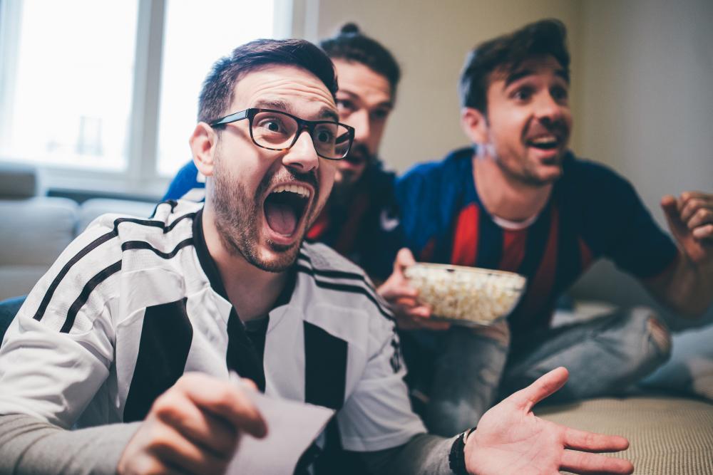 Männer jubeln über das im Fernsehen übertragene Fußballspiel.