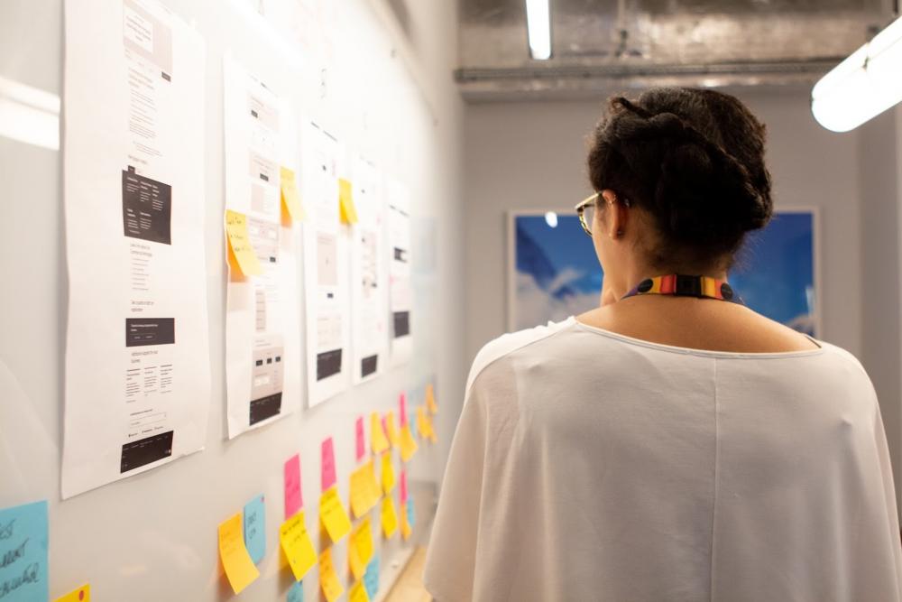 Frau von hinten vor einer Wand mit Post-its