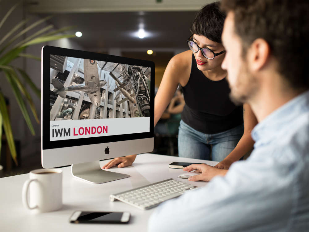 Mann und Frau diskutieren vor Computer über IWM Webseite