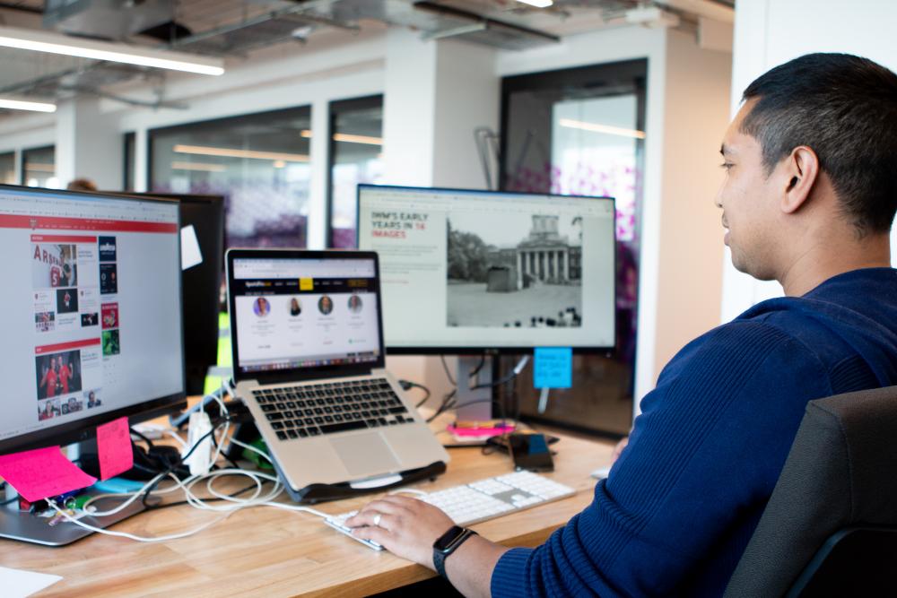 Mann sitzt vor 3 Screens und arbeitet an der Imperial War Museum Webseite