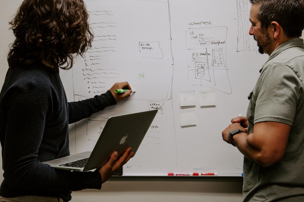 Mann und Frau diskutieren und analysieren vor einem Whiteboard