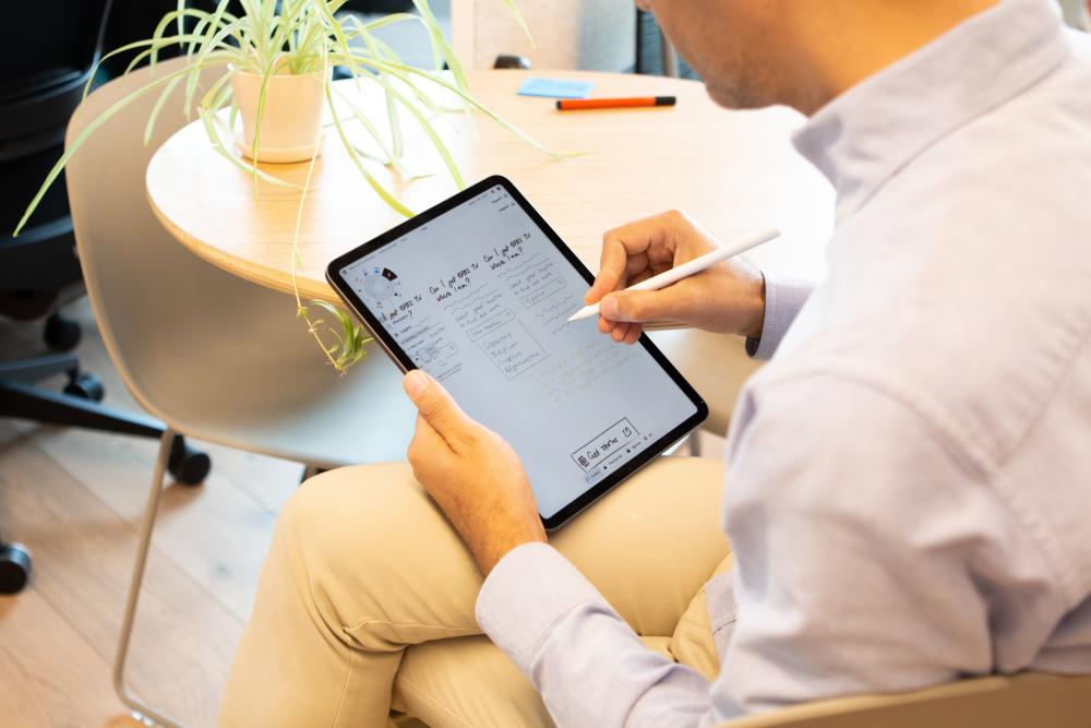 Mann schreibt auf IPad Notizen auf