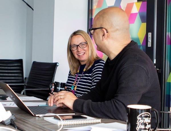 Male and female in a meeting room smiling