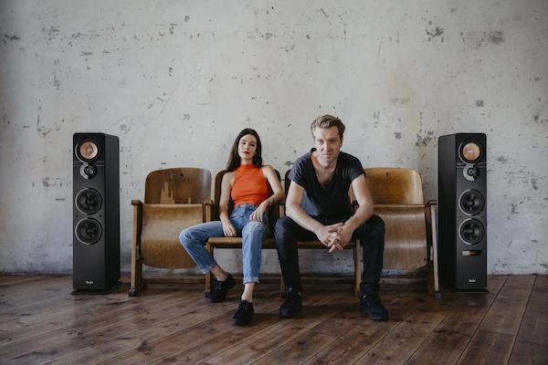 man and woman on sofa next to speakers