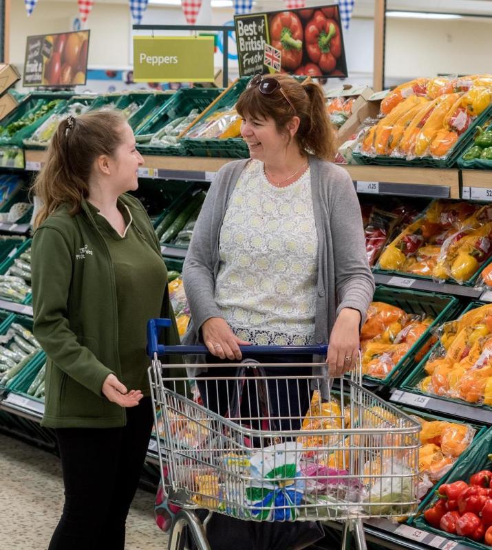 two ladies in a supermarket with shopping trolly having a chat