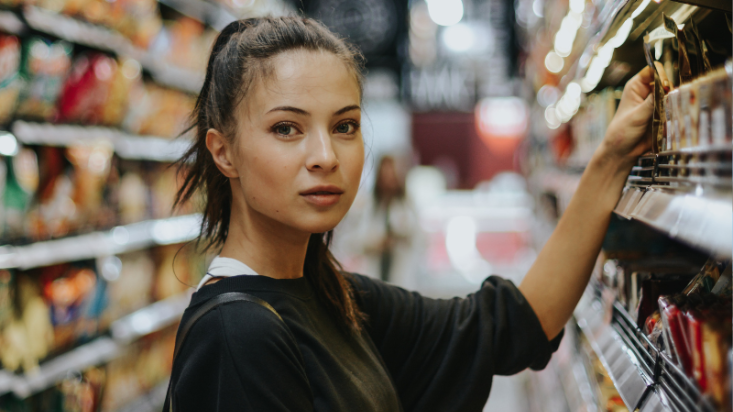 Woman browsing the supermarket shelves and looking into the camera